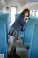 A woman in a school uniform leaning against a blue chair.